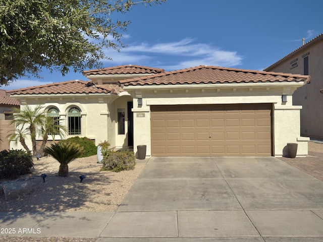 mediterranean / spanish home featuring an attached garage, driveway, a tile roof, and stucco siding