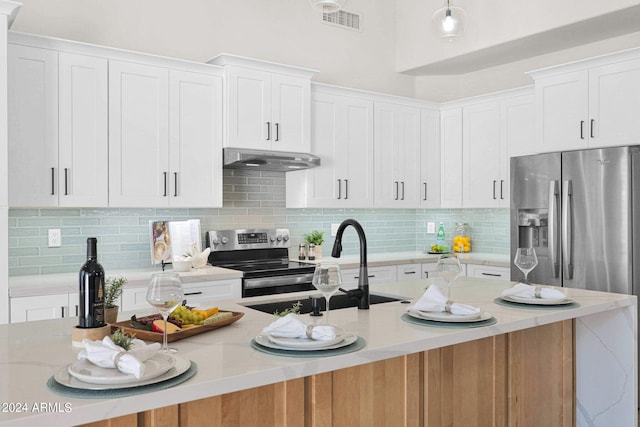 kitchen with an island with sink, backsplash, stainless steel appliances, white cabinets, and extractor fan