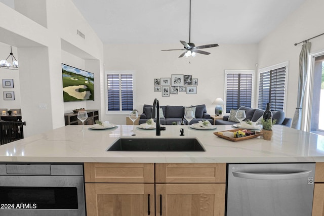 kitchen with sink, lofted ceiling, stainless steel dishwasher, light stone counters, and a center island with sink