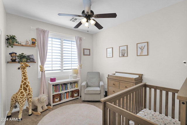 carpeted bedroom featuring ceiling fan and a nursery area