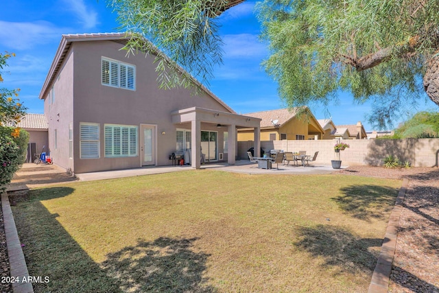 rear view of property featuring a patio and a lawn