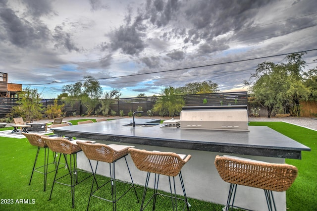 exterior space with outdoor dry bar, a grill, fence, exterior kitchen, and a yard