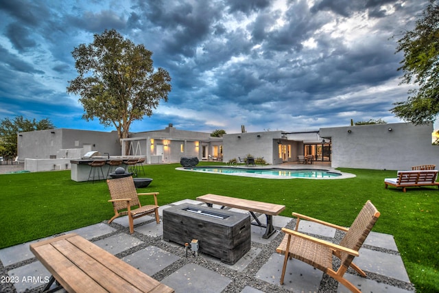 back of house with a yard, an outdoor fire pit, an outdoor pool, and a patio