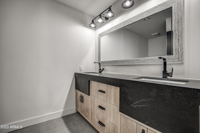 bathroom featuring double vanity, tile patterned floors, a sink, and baseboards