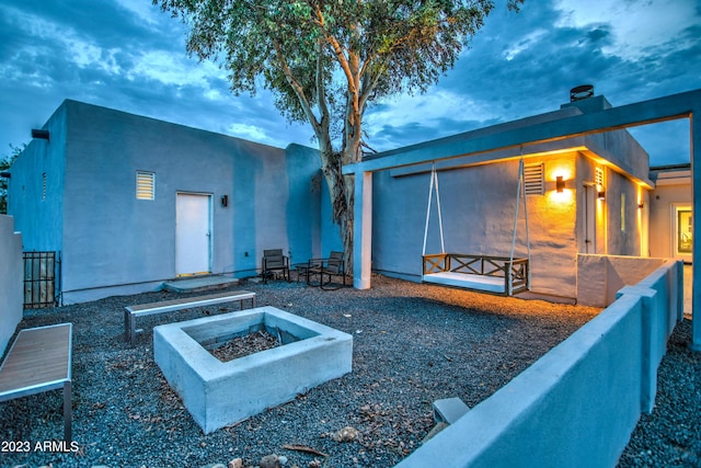 rear view of property featuring an outdoor fire pit and fence