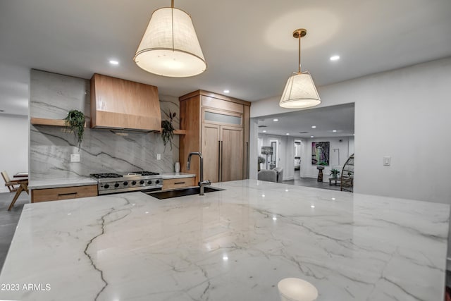 kitchen with range, light stone counters, wall chimney range hood, open shelves, and a sink