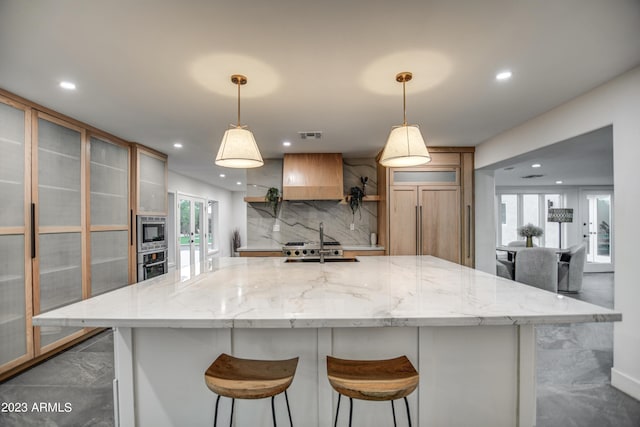 kitchen with tasteful backsplash, recessed lighting, custom range hood, built in appliances, and a large island with sink