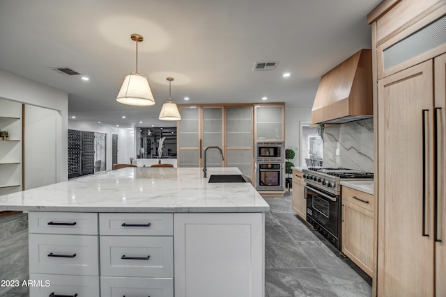 kitchen with a sink, visible vents, appliances with stainless steel finishes, wall chimney range hood, and decorative backsplash