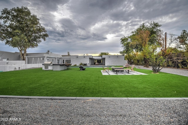 back of property with an outdoor fire pit, a patio area, a lawn, and fence