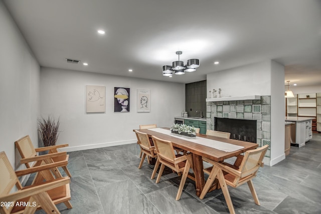 dining area with a tile fireplace, recessed lighting, visible vents, baseboards, and an inviting chandelier