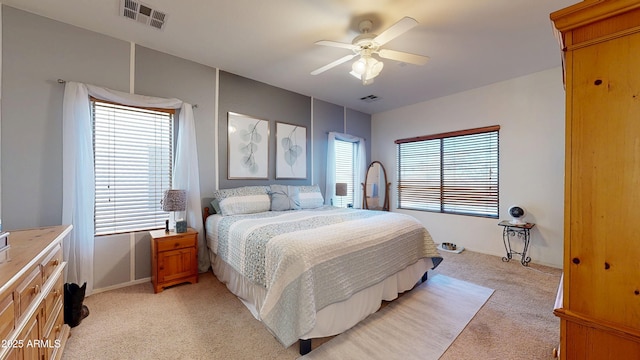 carpeted bedroom featuring multiple windows and ceiling fan