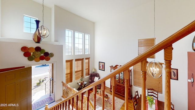 stairway with a high ceiling, hardwood / wood-style floors, and a chandelier