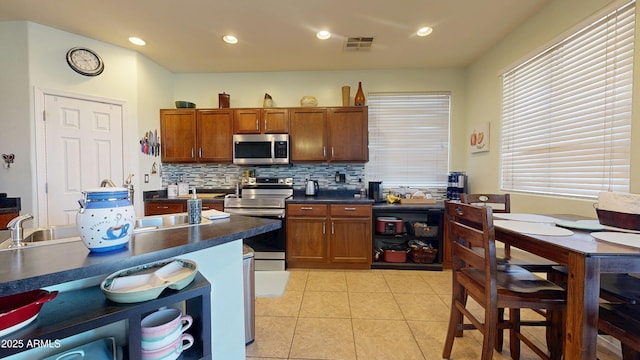 kitchen featuring stainless steel appliances, tasteful backsplash, sink, and light tile patterned floors