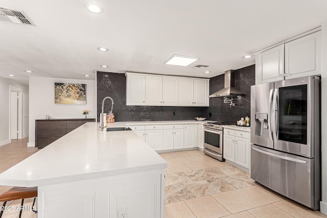 kitchen with white cabinetry, sink, wall chimney exhaust hood, an island with sink, and appliances with stainless steel finishes