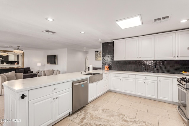 kitchen featuring white cabinets, kitchen peninsula, sink, and appliances with stainless steel finishes