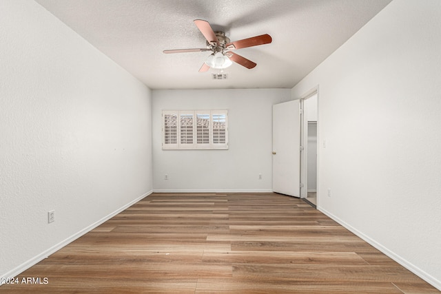 spare room featuring a textured ceiling, ceiling fan, and light hardwood / wood-style flooring