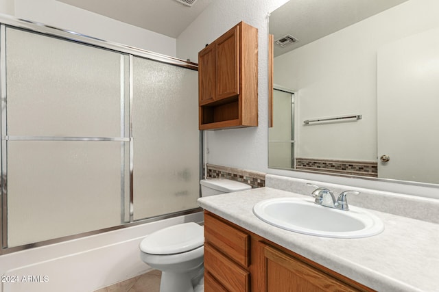 full bathroom featuring tile patterned flooring, bath / shower combo with glass door, vanity, and toilet