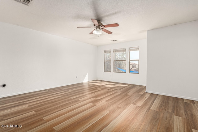 empty room with ceiling fan, a textured ceiling, and light hardwood / wood-style floors