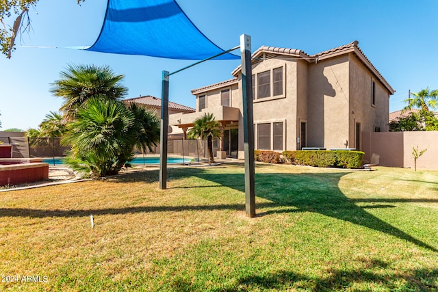 rear view of property featuring a fenced in pool and a yard