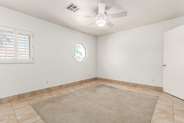 tiled empty room featuring ceiling fan and a textured ceiling