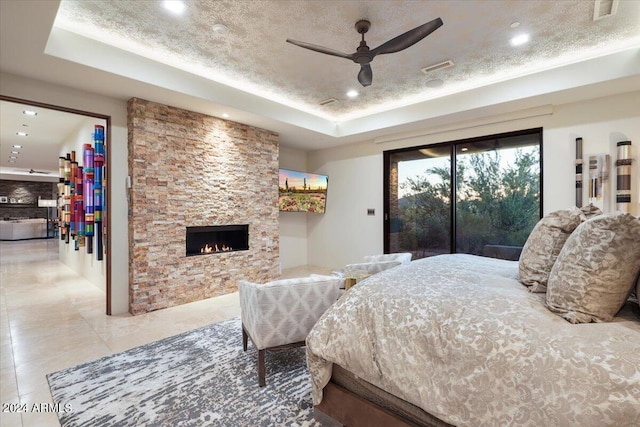 39254 N 104th Pl, Scottsdale, AZ 85262 - bedroom featuring a tray ceiling, access to outside, a fireplace, and a textured ceiling