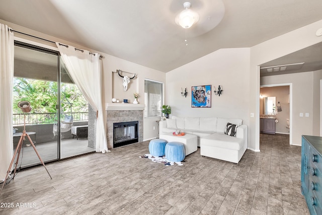 living room with lofted ceiling, light wood-type flooring, a fireplace, and baseboards