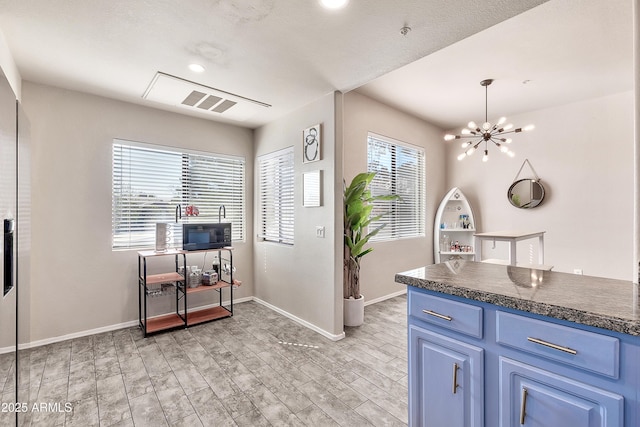 kitchen featuring light wood-type flooring, dark countertops, a healthy amount of sunlight, and blue cabinetry