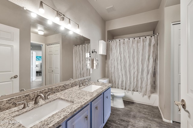 bathroom with toilet, double vanity, visible vents, and a sink