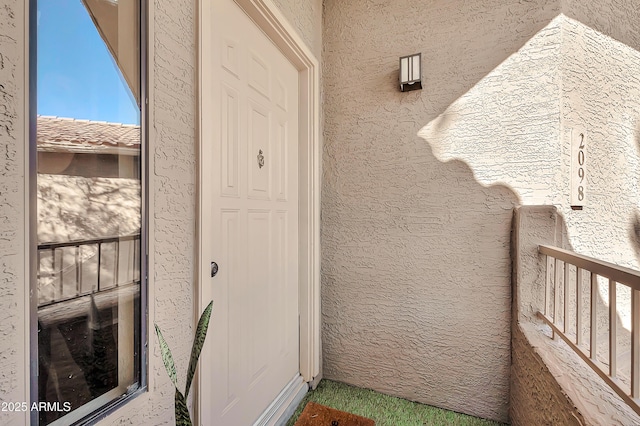 doorway to property with a balcony and stucco siding