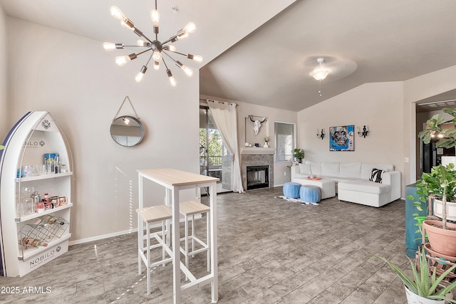 living room featuring baseboards, lofted ceiling, wood finished floors, a fireplace, and a chandelier