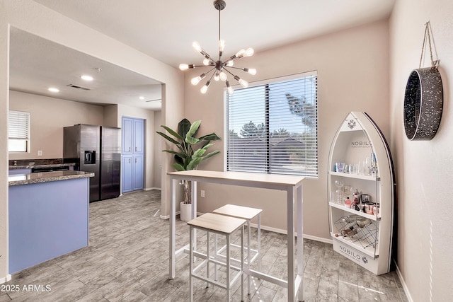 dining room featuring baseboards, visible vents, light wood-style flooring, and an inviting chandelier