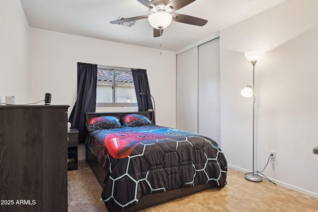 tiled bedroom with a closet, baseboards, and a ceiling fan