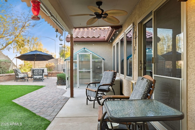 view of patio / terrace featuring fence, a ceiling fan, and an outbuilding