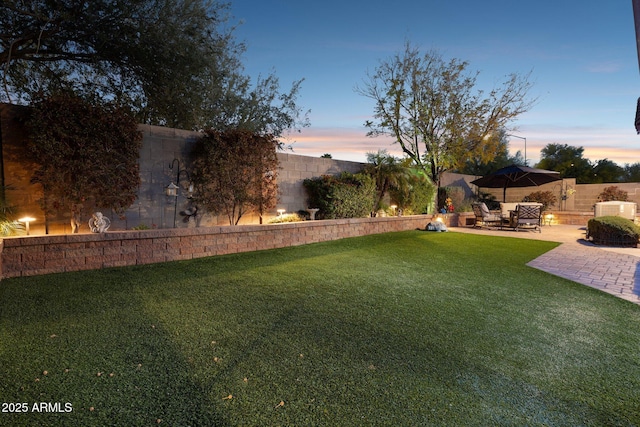 yard at dusk featuring a patio area and a fenced backyard