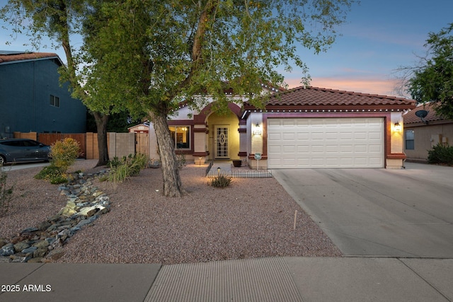 view of front facade with a tiled roof, a garage, concrete driveway, fence, and stucco siding