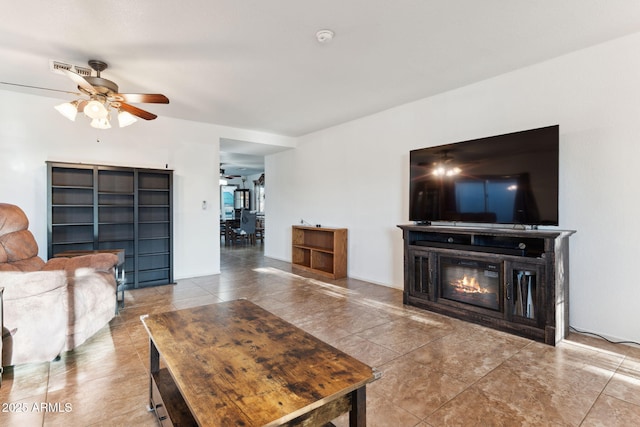 tiled living area with a glass covered fireplace and a ceiling fan
