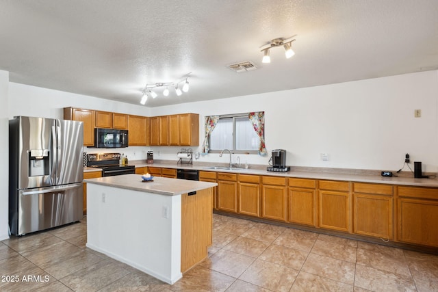 kitchen with visible vents, a sink, light countertops, brown cabinetry, and black appliances