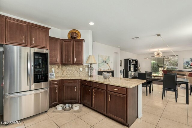 kitchen with smart refrigerator, light tile patterned flooring, arched walkways, a peninsula, and tasteful backsplash