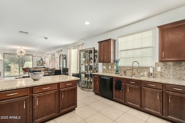 kitchen featuring light stone counters, tasteful backsplash, a sink, light tile patterned floors, and black dishwasher