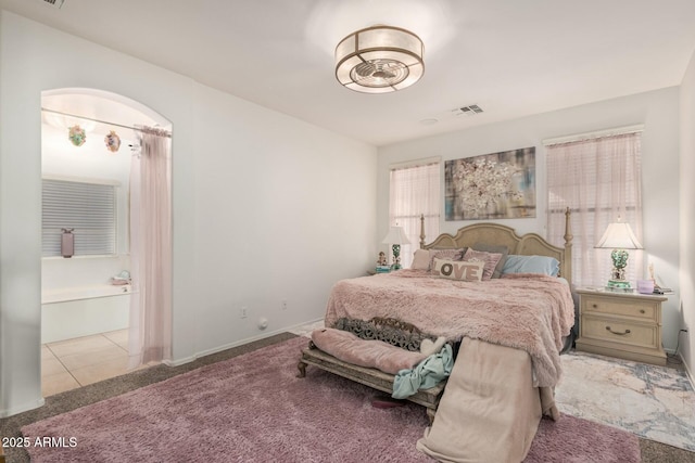 carpeted bedroom featuring visible vents, baseboards, and connected bathroom