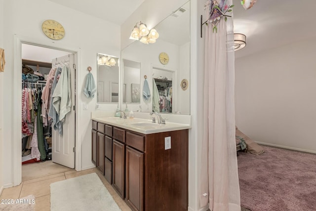 full bathroom with a walk in closet, visible vents, a sink, and double vanity