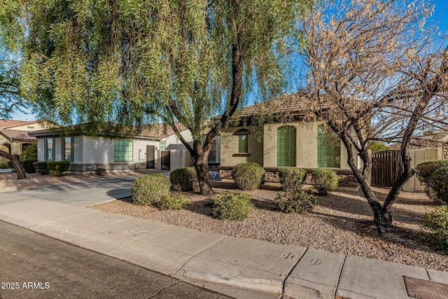 ranch-style house featuring stucco siding and fence