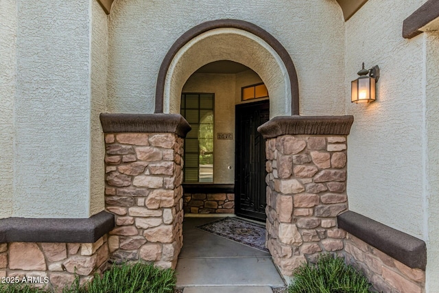 property entrance with stucco siding and stone siding