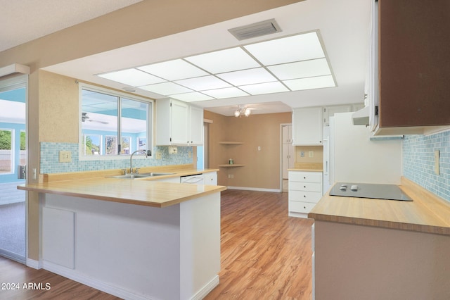 kitchen with kitchen peninsula, tasteful backsplash, white cabinetry, light hardwood / wood-style flooring, and sink