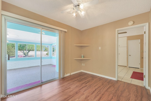 unfurnished room featuring a textured ceiling, light wood-type flooring, and ceiling fan