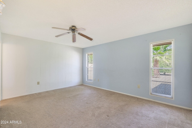 spare room featuring light carpet, plenty of natural light, and ceiling fan