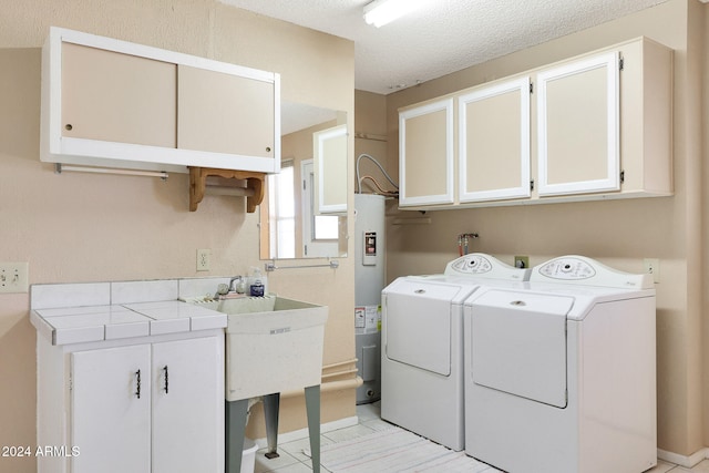 laundry room featuring cabinets, electric water heater, a textured ceiling, washing machine and dryer, and sink