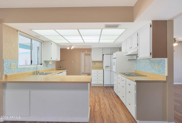 kitchen featuring decorative backsplash, kitchen peninsula, sink, white refrigerator with ice dispenser, and light hardwood / wood-style floors