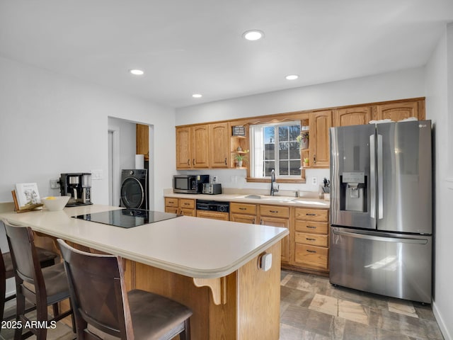 kitchen featuring appliances with stainless steel finishes, washer / dryer, sink, a kitchen breakfast bar, and kitchen peninsula