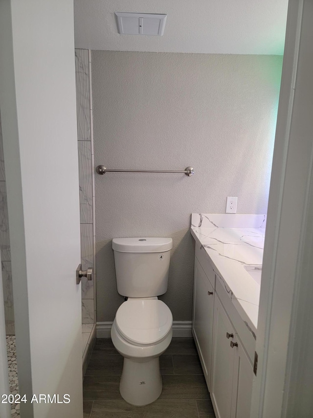 bathroom with hardwood / wood-style floors, vanity, toilet, and walk in shower